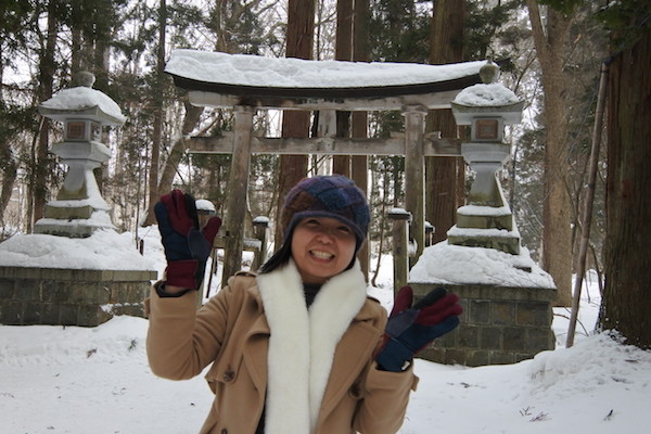 雪帽子をかぶった鳥居をバックに